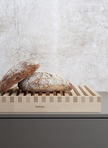 Bread crumbs disappear through the cutting board grid into the collection tray